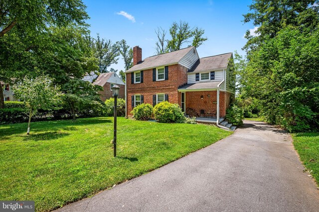 808 Olmstead Rd, Baltimore, MD 21208 - view of front facade featuring brick siding, a chimney, a front yard, and asphalt driveway