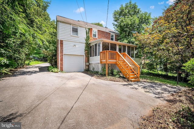 808 Olmstead Rd, Baltimore, MD 21208 - view of front of home featuring a sunroom, an attached garage, brick siding, and driveway