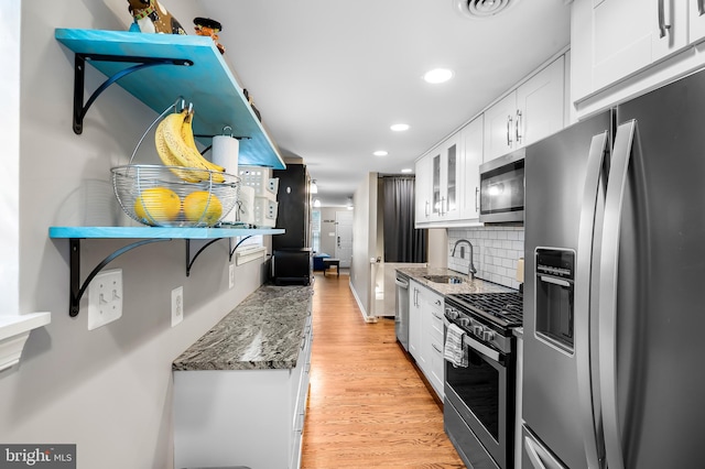2503 Eastern Ave, Baltimore, MD 21224 - kitchen with appliances with stainless steel finishes, white cabinetry, light wood-style floors, decorative backsplash, and light stone counters