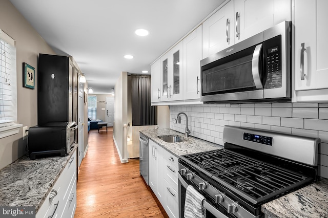 2503 Eastern Ave, Baltimore, MD 21224 - kitchen featuring stainless steel appliances, white cabinets, light wood-style flooring, decorative backsplash, and light stone countertops