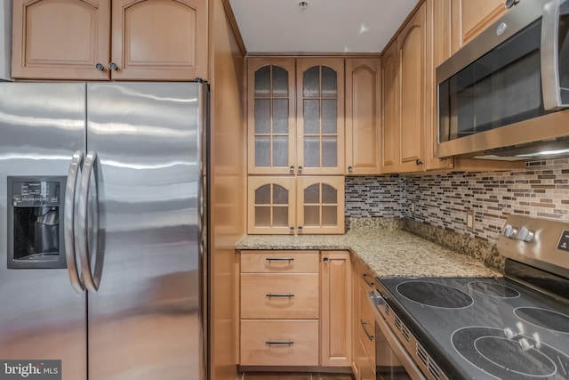 1458 Columbia Rd NW Unit 109, Washington, DC 20009 - kitchen featuring appliances with stainless steel finishes, light stone counters, backsplash, and glass insert cabinets