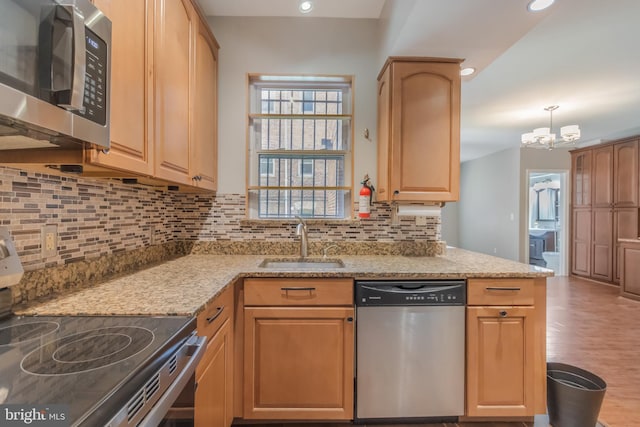 1458 Columbia Rd NW Unit 109, Washington, DC 20009 - kitchen featuring appliances with stainless steel finishes, decorative backsplash, a chandelier, light stone countertops, and wood finished floors