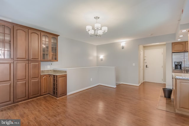 1458 Columbia Rd NW Unit 109, Washington, DC 20009 - kitchen featuring stainless steel refrigerator with ice dispenser, a chandelier, light wood-style flooring, brown cabinetry, and glass insert cabinets