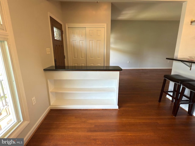 1233 Knightswood Rd, Baltimore, MD 21239 - kitchen featuring dark wood-style floors, dark countertops, a breakfast bar area, and a peninsula