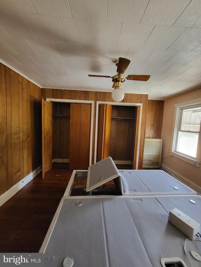 542 S 14 1/2 St, Reading, PA 19602 - bedroom featuring dark wood-style flooring, wood walls, multiple closets, and a ceiling fan