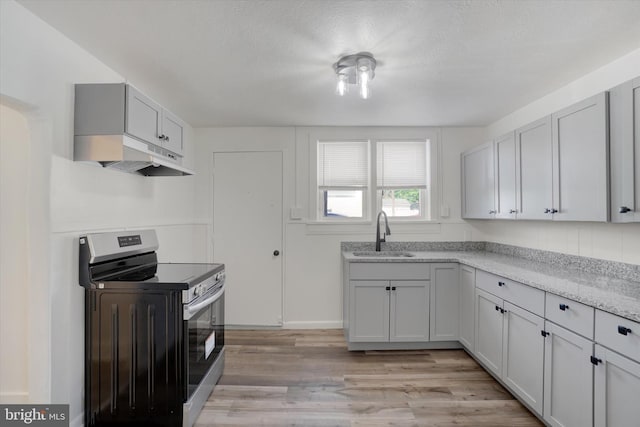 1221 W Heiges St, York, PA 17404 - kitchen featuring electric stove, under cabinet range hood, light wood-style floors, and light stone counters