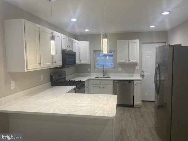 224 N Rose St, Baltimore, MD 21224 - kitchen with stainless steel appliances, a peninsula, light countertops, wood finished floors, and decorative light fixtures