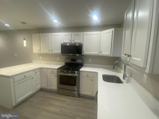 224 N Rose St, Baltimore, MD 21224 - kitchen with appliances with stainless steel finishes, a peninsula, white cabinets, light wood-style flooring, and light countertops