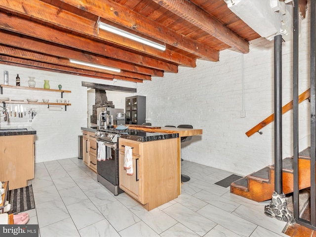 23 W 5th St, Frederick, MD 21701 - kitchen with light marble finish floors, brick wall, dark countertops, stainless steel range with gas stovetop, and a wooden ceiling with exposed beams