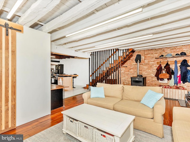 23 W 5th St, Frederick, MD 21701 - living area featuring a wood stove, hardwood / wood-style flooring, brick wall, beam ceiling, and a barn door