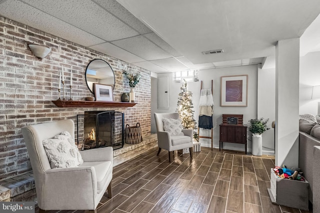 69 Plymouth Rd, Sicklerville, NJ 08081 - sitting room with wood tiled floors, a fireplace, electric panel, a drop ceiling, and brick wall