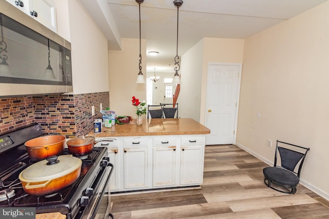 16 S Kresson St, Baltimore, MD 21224 - kitchen featuring stainless steel appliances, a peninsula, white cabinetry, light wood-type flooring, and pendant lighting