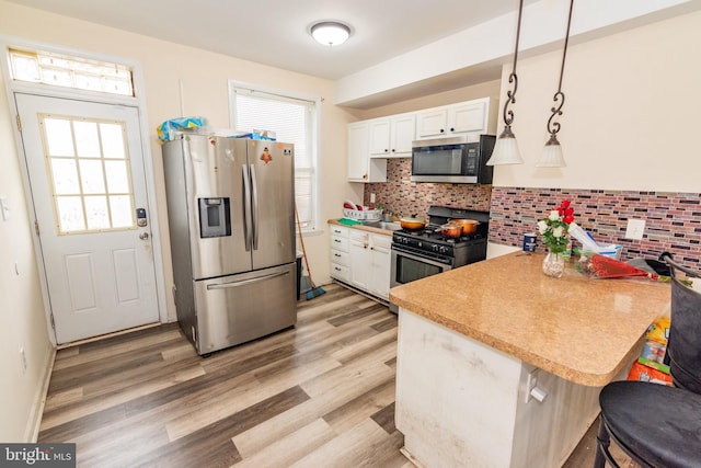 16 S Kresson St, Baltimore, MD 21224 - kitchen featuring appliances with stainless steel finishes, white cabinetry, decorative backsplash, a kitchen breakfast bar, and healthy amount of natural light