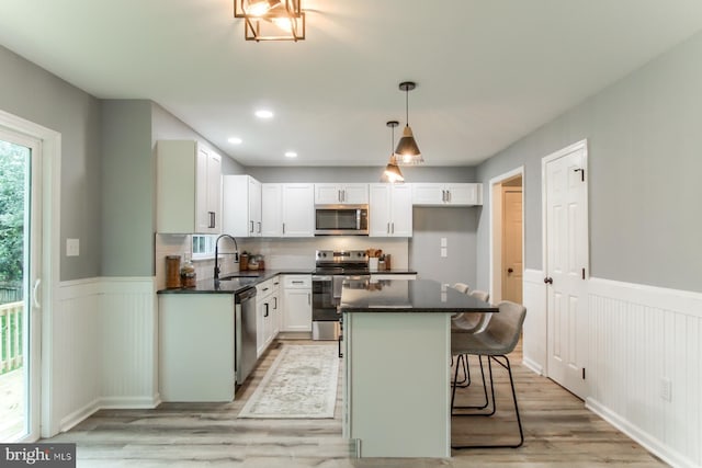 128 Azalea Dr, Hershey, PA 17033 - kitchen with appliances with stainless steel finishes, light wood finished floors, wainscoting, white cabinets, and a kitchen bar