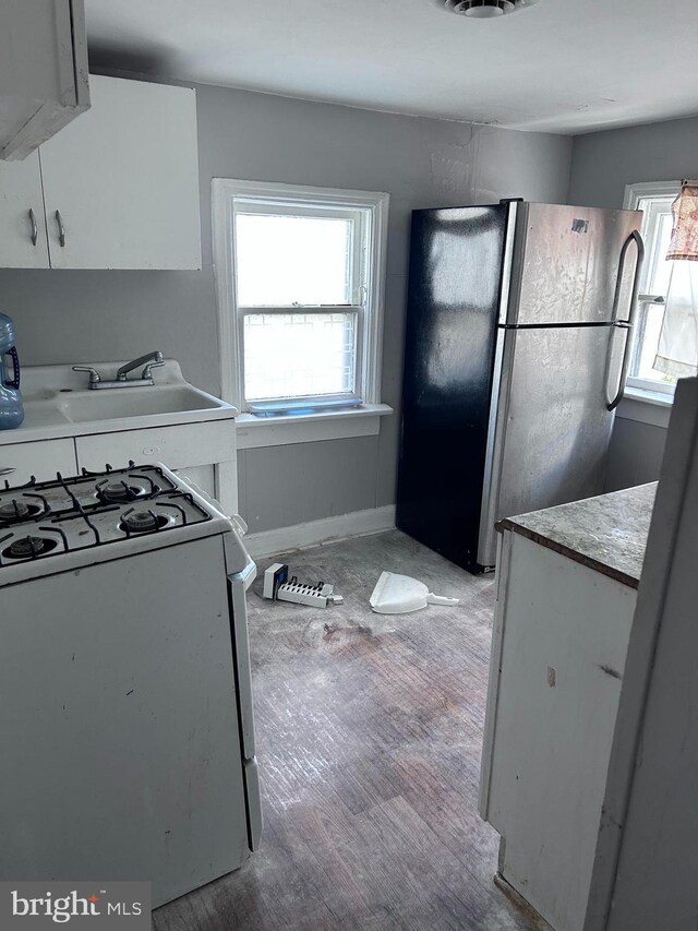 723 N Broad St, Woodbury, NJ 08096 - kitchen with freestanding refrigerator, white gas range oven, range hood, light wood-style flooring, and light countertops