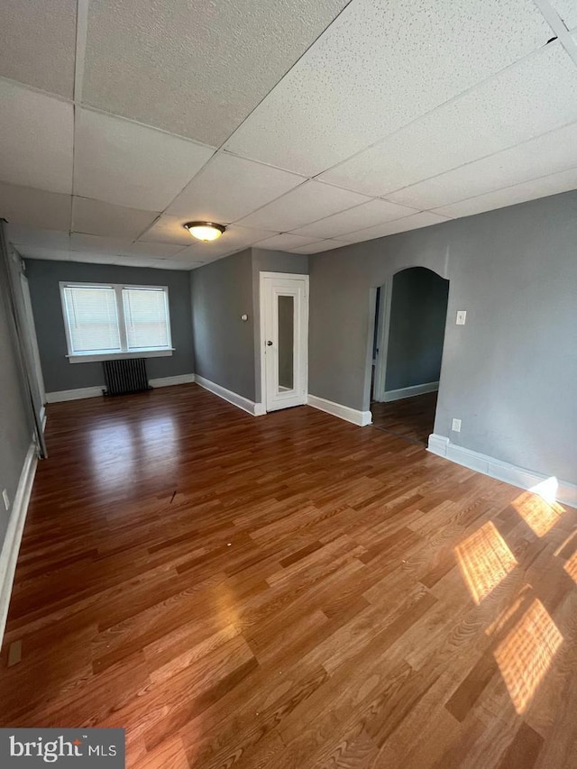 723 N Broad St, Woodbury, NJ 08096 - unfurnished room featuring radiator, arched walkways, wood finished floors, and a drop ceiling