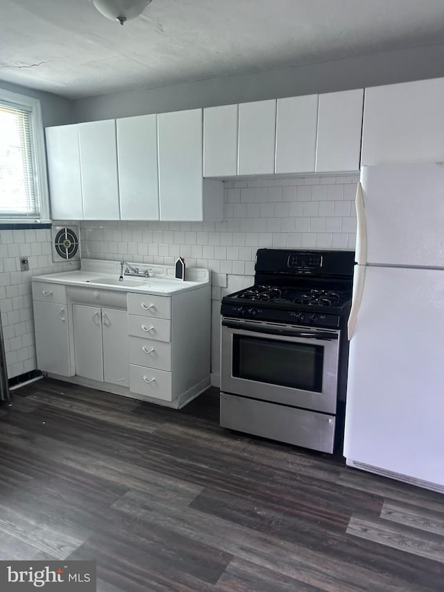 723 N Broad St, Woodbury, NJ 08096 - kitchen with freestanding refrigerator, gas stove, white cabinets, light countertops, and dark wood-style floors