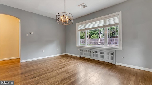 2705 W Gordon, Allentown, PA 18104 - empty room with radiator heating unit, arched walkways, hardwood / wood-style flooring, and a chandelier