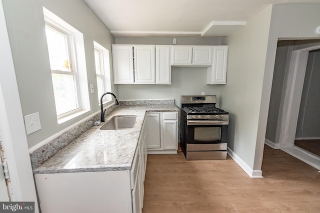 631 Saint Anns Ave, Baltimore, MD 21218 - kitchen with stainless steel range with gas cooktop, white cabinetry, light wood finished floors, and light stone countertops