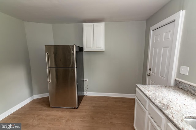631 Saint Anns Ave, Baltimore, MD 21218 - kitchen with freestanding refrigerator, light wood-style flooring, light stone countertops, and white cabinetry