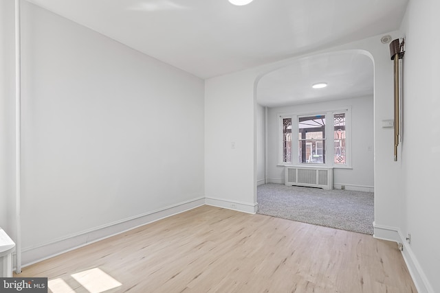 1439 S 28th St, Philadelphia, PA 19146 - spare room featuring arched walkways, radiator heating unit, and light wood-style floors