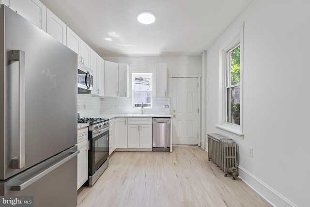 1439 S 28th St, Philadelphia, PA 19146 - kitchen with stainless steel appliances, radiator heating unit, tasteful backsplash, and white cabinetry