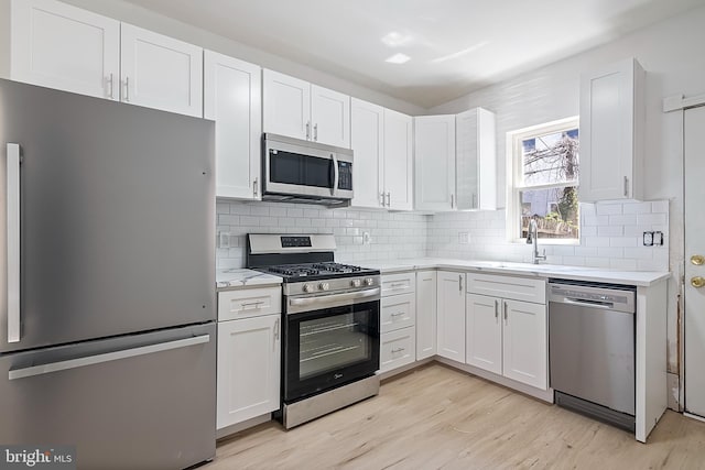1439 S 28th St, Philadelphia, PA 19146 - kitchen featuring stainless steel appliances, light wood-style flooring, white cabinetry, and decorative backsplash