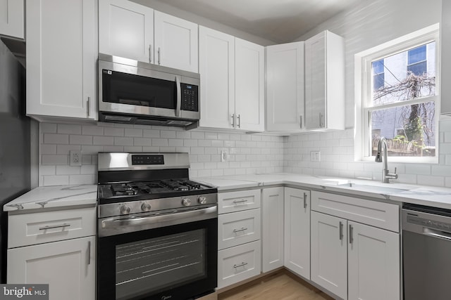 1439 S 28th St, Philadelphia, PA 19146 - kitchen featuring appliances with stainless steel finishes, white cabinetry, and light stone countertops