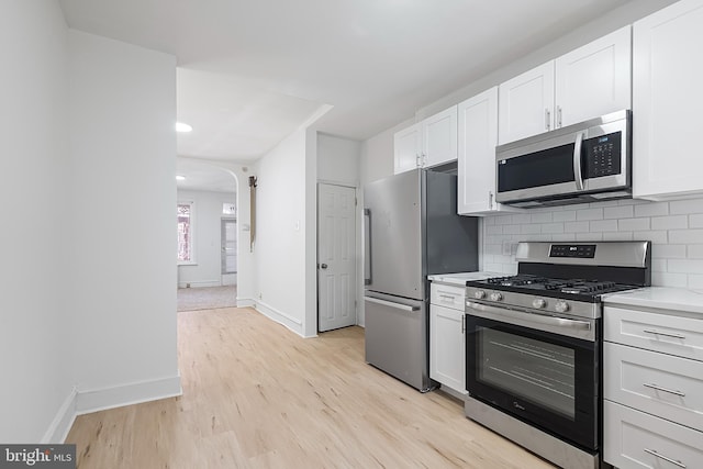 1439 S 28th St, Philadelphia, PA 19146 - kitchen with appliances with stainless steel finishes, light wood-type flooring, backsplash, white cabinetry, and light countertops