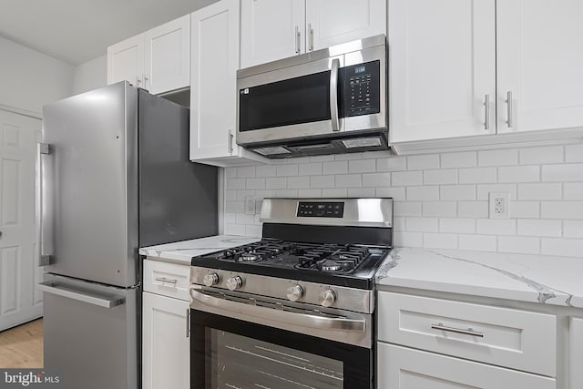 1439 S 28th St, Philadelphia, PA 19146 - kitchen with appliances with stainless steel finishes, white cabinets, light stone counters, and backsplash