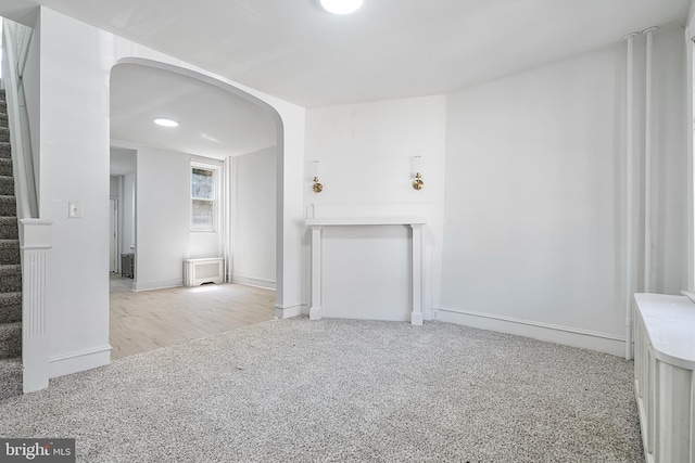 1439 S 28th St, Philadelphia, PA 19146 - unfurnished living room with arched walkways, carpet floors, stairs, and radiator heating unit