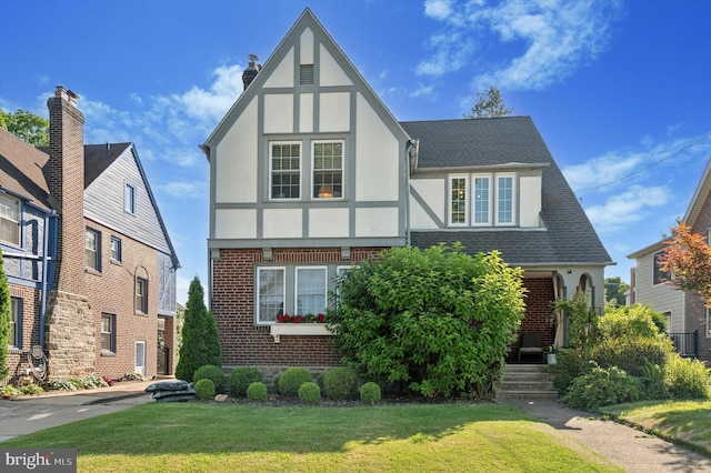828 Turner Ave, Drexel Hill, PA 19026 - english style home featuring stucco siding, brick siding, a front yard, and roof with shingles