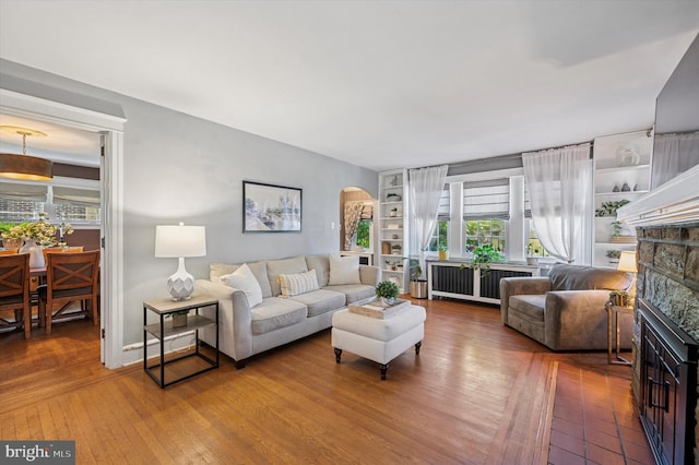 828 Turner Ave, Drexel Hill, PA 19026 - living area with radiator heating unit, arched walkways, a stone fireplace, hardwood / wood-style floors, and built in shelves