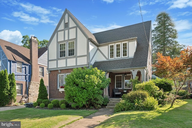828 Turner Ave, Drexel Hill, PA 19026 - tudor home featuring stucco siding, a front yard, a porch, and roof with shingles