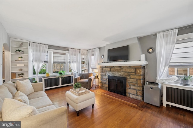 828 Turner Ave, Drexel Hill, PA 19026 - living area featuring radiator heating unit, healthy amount of natural light, wood finished floors, and a fireplace