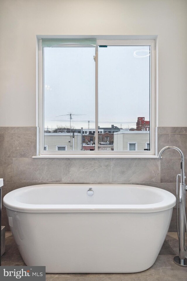 1448 N Myrtlewood St, Philadelphia, PA 19121 - bathroom featuring tile walls, a freestanding tub, and wainscoting