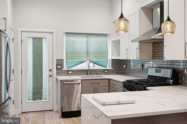 1448 N Myrtlewood St, Philadelphia, PA 19121 - kitchen with wall chimney range hood, stainless steel appliances, light stone counters, and pendant lighting