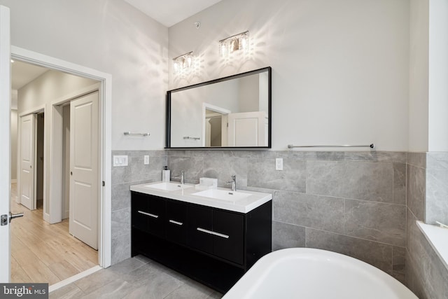 1448 N Myrtlewood St, Philadelphia, PA 19121 - full bathroom featuring tile walls, a soaking tub, double vanity, and wainscoting