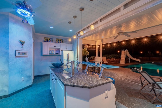 2865 Proffit Rd, Charlottesville, VA 22911 - kitchen with a ceiling fan, dark stone countertops, white cabinetry, freestanding refrigerator, and a center island