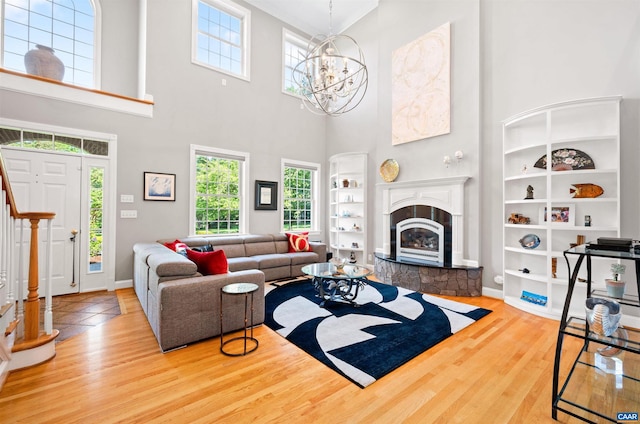 2865 Proffit Rd, Charlottesville, VA 22911 - living room featuring built in features, wood finished floors, a glass covered fireplace, a towering ceiling, and a chandelier