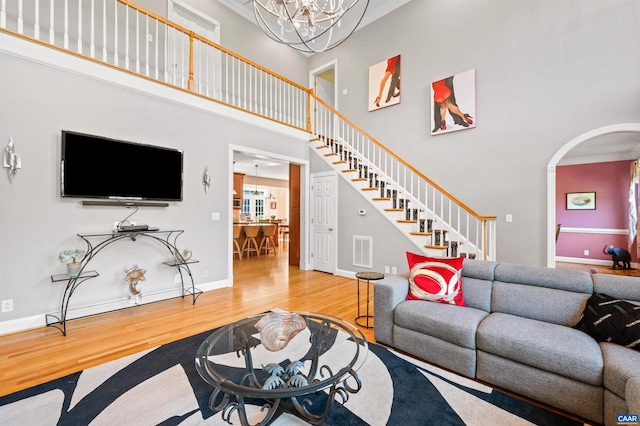 2865 Proffit Rd, Charlottesville, VA 22911 - living room with wood finished floors, a towering ceiling, stairs, a chandelier, and arched walkways