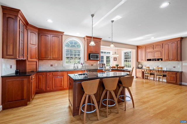 2865 Proffit Rd, Charlottesville, VA 22911 - kitchen with stainless steel microwave, tasteful backsplash, a kitchen island with sink, light wood-style floors, and a kitchen breakfast bar
