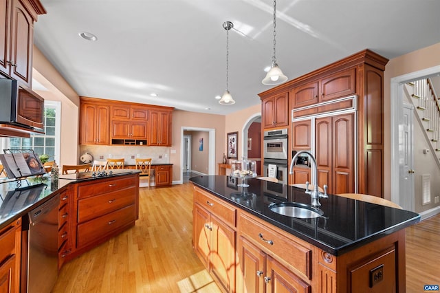 2865 Proffit Rd, Charlottesville, VA 22911 - kitchen with stainless steel appliances, a kitchen island with sink, light wood finished floors, hanging light fixtures, and arched walkways