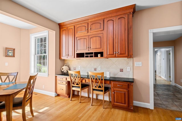 2865 Proffit Rd, Charlottesville, VA 22911 - kitchen featuring built in desk, tasteful backsplash, dark countertops, and light wood-style floors