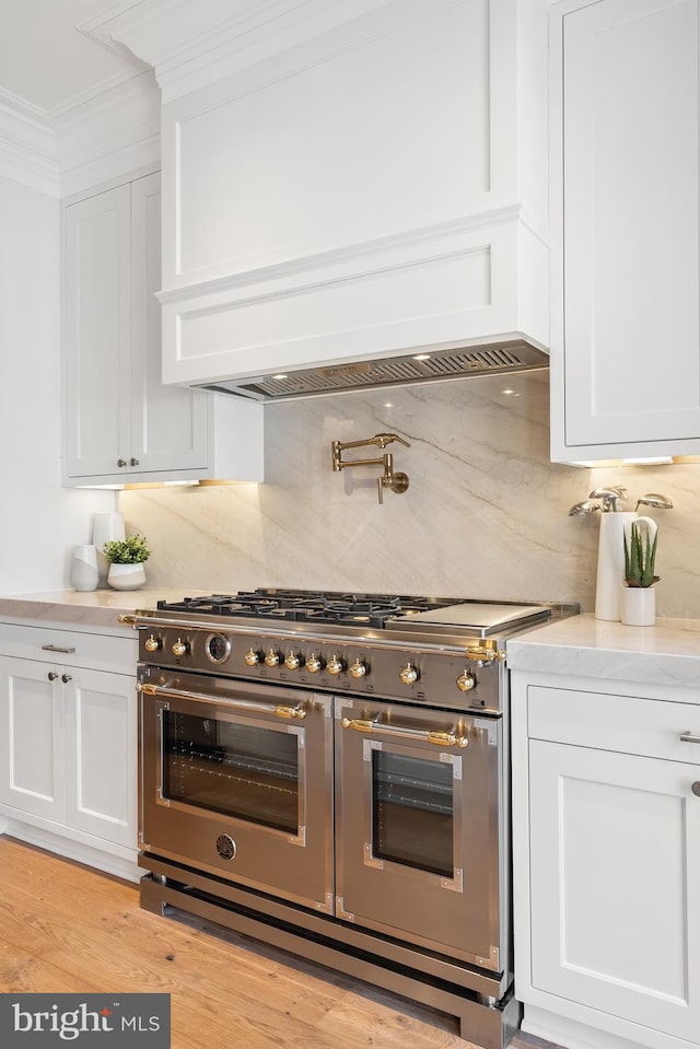 1720 15th St NW, Washington, DC 20009 - kitchen featuring range with two ovens, white cabinets, decorative backsplash, ornamental molding, and light wood-type flooring