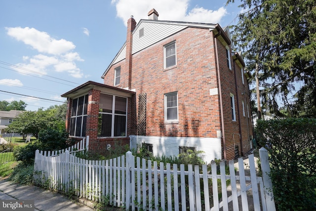 6339 Frederick Rd, Baltimore, MD 21228 - view of property exterior featuring brick siding, a chimney, and a sunroom