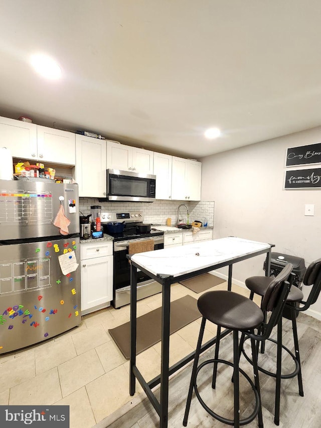 7034 N Broad St, Philadelphia, PA 19126 - kitchen with stainless steel appliances, backsplash, white cabinets, and light tile patterned floors