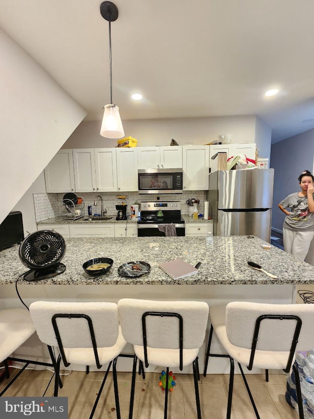 7034 N Broad St, Philadelphia, PA 19126 - kitchen with stainless steel appliances, a breakfast bar area, tasteful backsplash, light stone counters, and decorative light fixtures