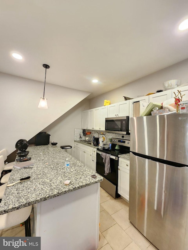 7034 N Broad St, Philadelphia, PA 19126 - kitchen with appliances with stainless steel finishes, a peninsula, white cabinets, decorative backsplash, and decorative light fixtures