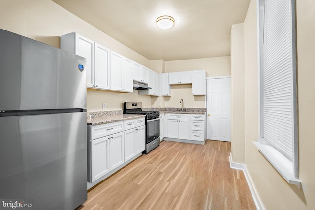 409 N Franklin St, Wilmington, DE 19805 - kitchen featuring appliances with stainless steel finishes, under cabinet range hood, light wood-type flooring, white cabinets, and light stone countertops